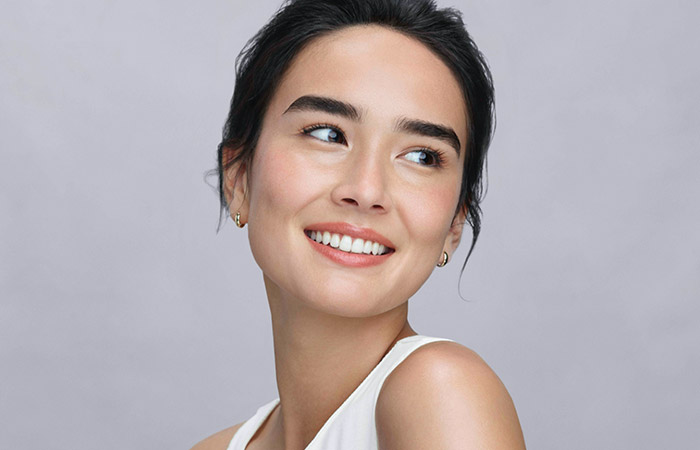 Mano de una mujer sosteniendo un recipiente de vidrio de laboratorio. Artistry; ingredientes naturales probados para el cuidado de la piel 